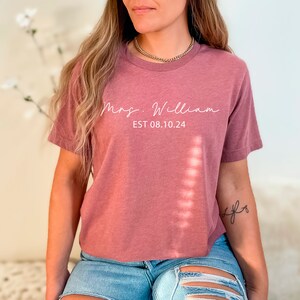May include: A mauve cropped t-shirt with the text "Mrs. William EST 08.10.24" in white lettering.