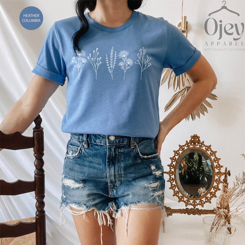 May include: A light blue t-shirt with a white floral design. The shirt is made of a soft, comfortable material and has a relaxed fit.