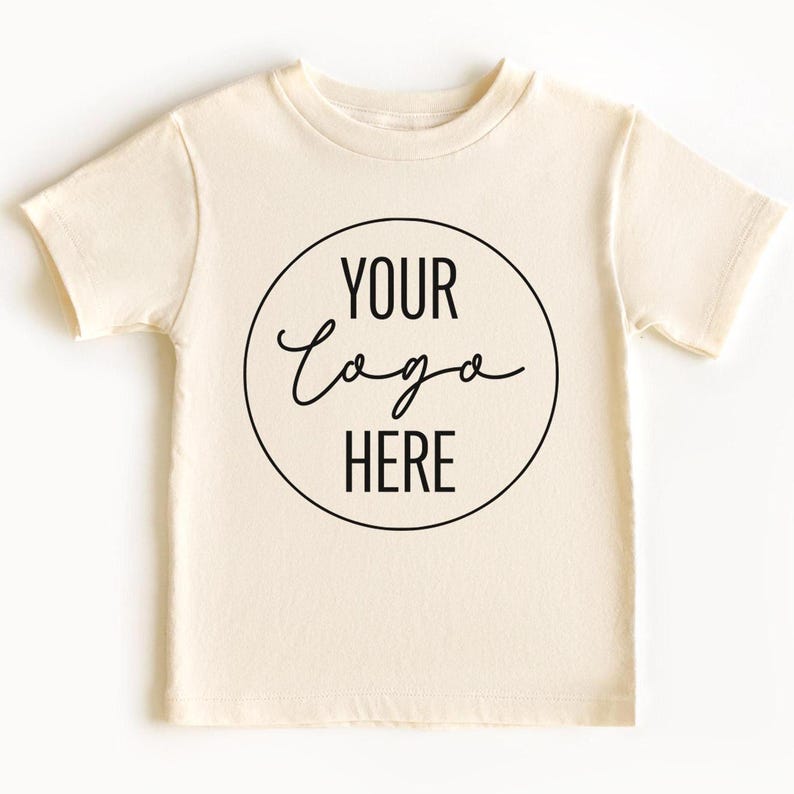 May include: A plain white t-shirt with a black circle containing the text "YOUR LOGO HERE" in a handwritten font.