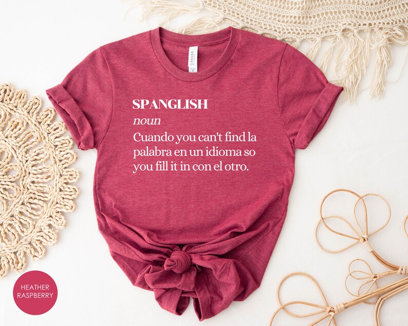 Puede incluir: Una camiseta color granate con la palabra "SPANGLISH" definida como "Cuando you can't find la palabra en un idioma so you fill it in con el otro."