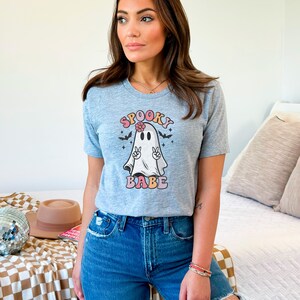 May include: A gray t-shirt with a graphic of a ghost with a flower in its hair and the text "Spooky Babe" in colorful letters.
