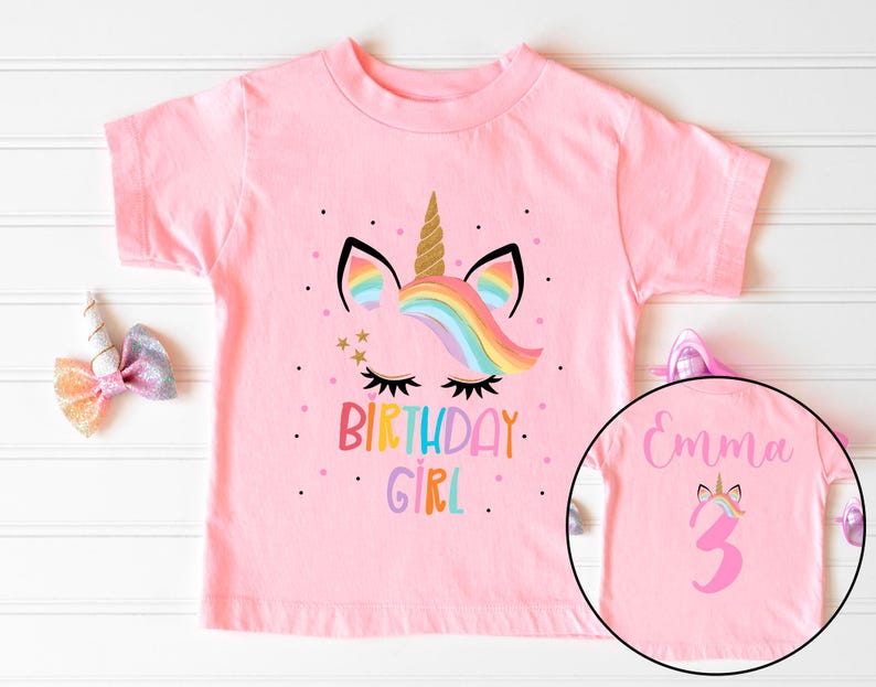 May include: Pink short-sleeved t-shirt with a unicorn graphic and the text "Birthday Girl". The back of the shirt has the name "Emma" and the number "3" in pink.