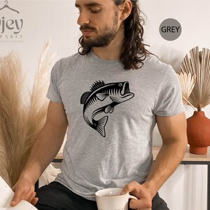 May include: A grey t-shirt featuring a black graphic of a bass fish leaping out of the water. The text "GREY" is in a white circle on the right side of the image.