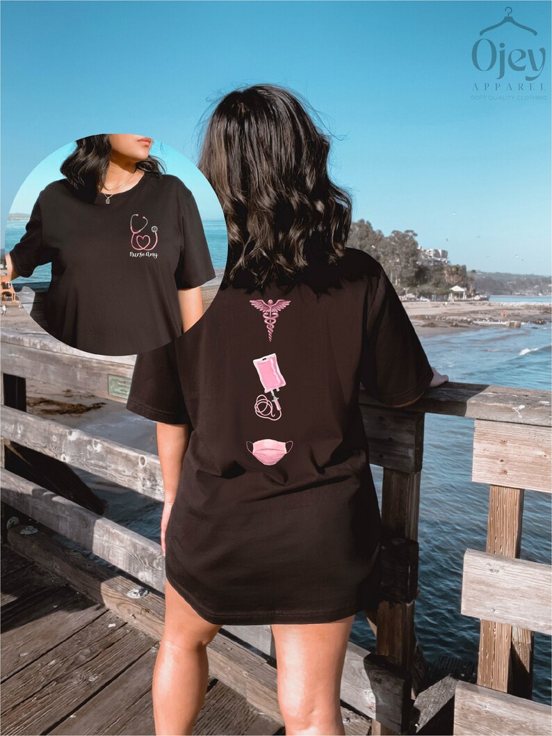 May include: Black oversized t-shirt with a pink medical symbol, a pink IV bag, and a pink face mask on the back. The front of the shirt has a pink stethoscope and heart with the text "Nurse-ing" on the front.