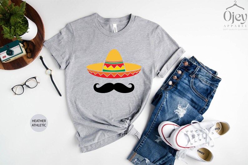 May include: A heather grey t-shirt with a black mustache and a yellow, red, green, and orange sombrero.