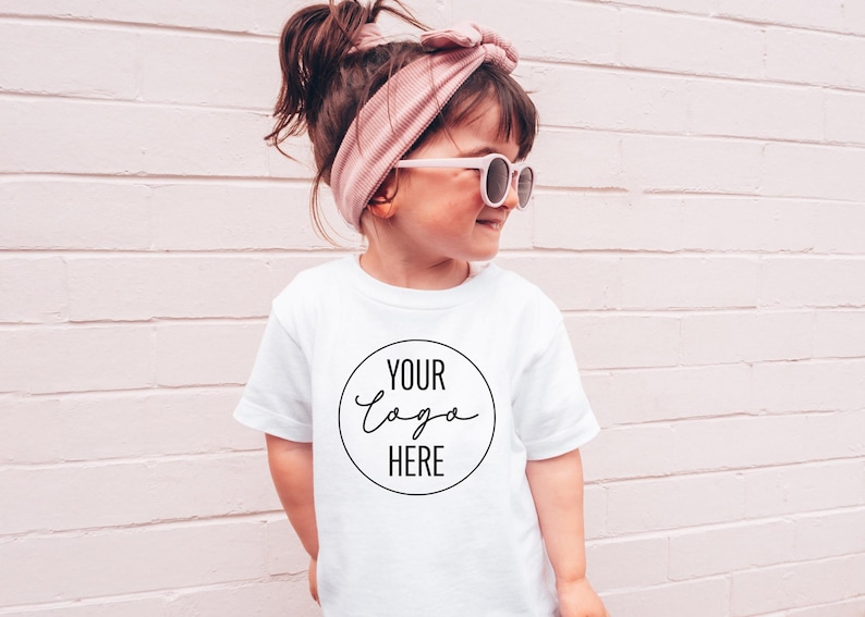 May include: A white t-shirt with a black circle and the text "YOUR LOGO HERE" in a handwritten font.