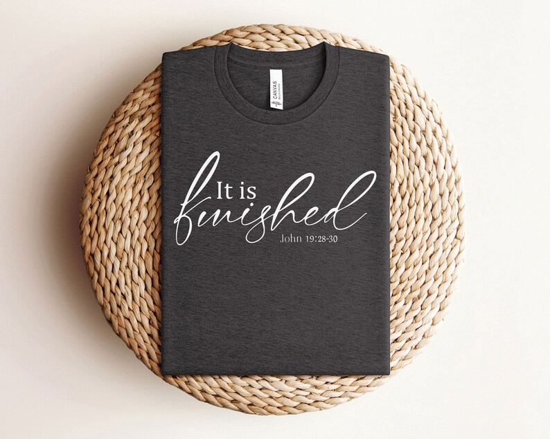 May include: A dark gray t-shirt with the text "It is finished" in white cursive lettering and the scripture reference "John 19:28-30" underneath.