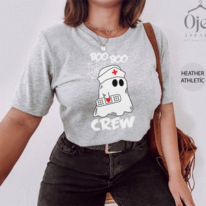 May include: A grey t-shirt with the text "Boo Boo Crew" and a cartoon ghost wearing a nurse's hat and holding a bandage with a heart on it.