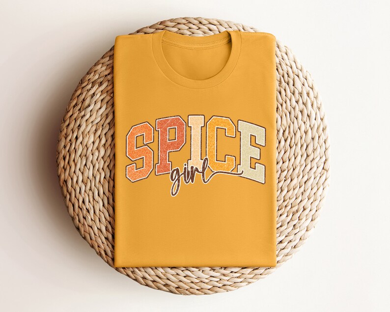 May include: A mustard yellow t-shirt with the text "SPICE girl" in a retro font with orange, red, and brown colors.