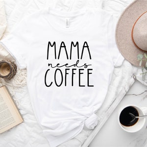 May include: White t-shirt with black text that reads "Mama needs coffee".