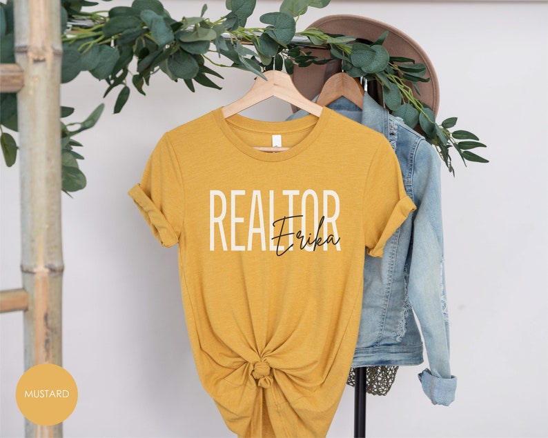 Peut inclure: Un t-shirt jaune moutarde avec le texte "REALTOR Erika" imprim&eacute; en blanc et noir.