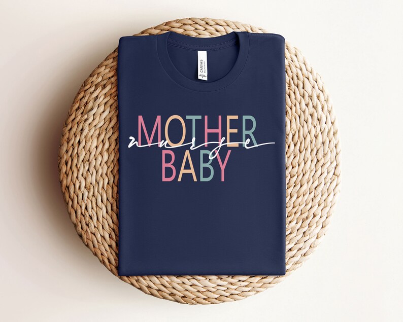 Puede incluir: Una camiseta azul marino con el texto "MOTHER of a BABY" en letras de colores. Las letras son de diferentes colores, incluyendo rosa, azul claro y amarillo.