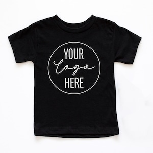 May include: Black short-sleeved t-shirt with a white circle on the front that says "YOUR LOGO HERE" in a handwritten font.