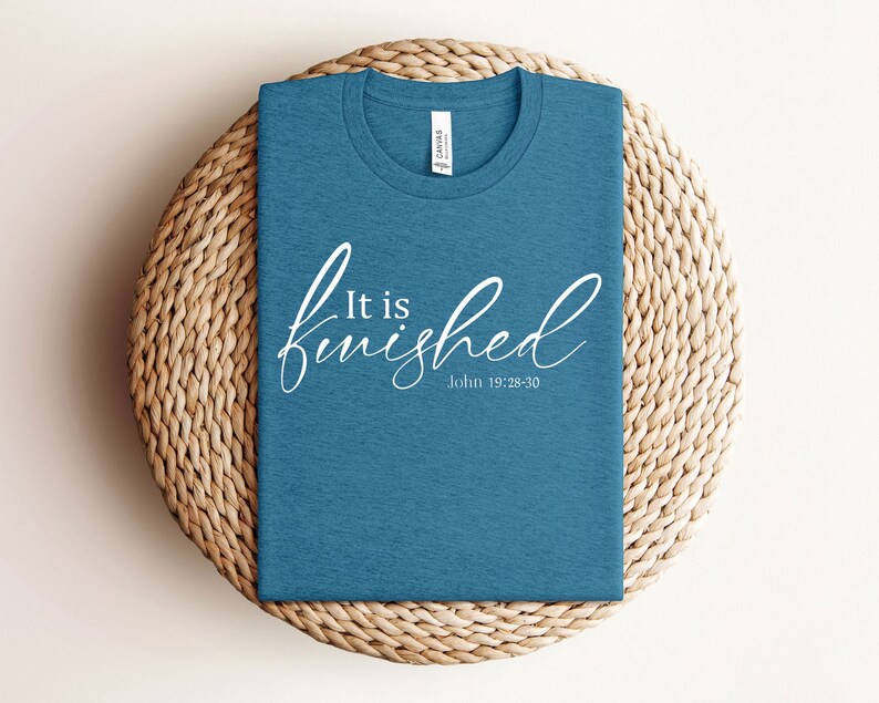 May include: A teal blue t-shirt with the text "It is finished" in white cursive lettering and the scripture reference "John 19:28-30" underneath.