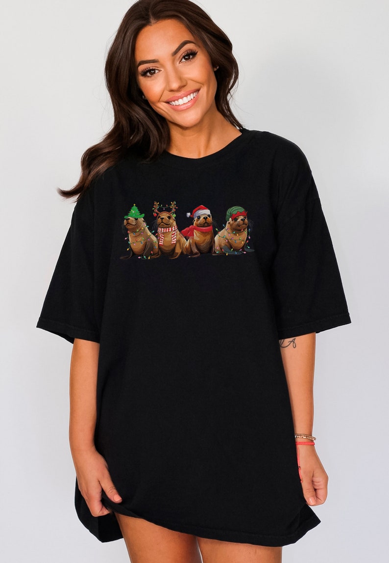 May include: A black t-shirt with a graphic of four seals wearing Christmas hats and decorations. The seals are wearing a Santa hat, a reindeer hat, a green elf hat, and a green and red scarf.