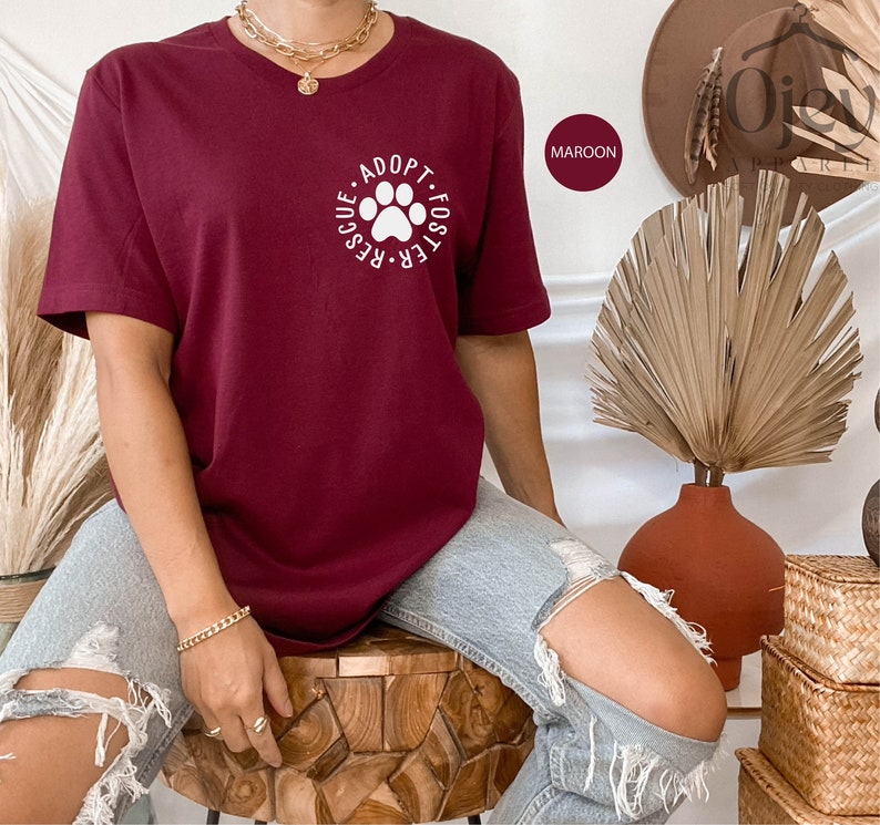 May include: A maroon t-shirt with a white paw print graphic and the text "Adopt. Foster. Rescue."
