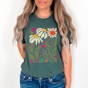 May include: A dark green t-shirt with a floral print featuring white, yellow, orange, pink, and green flowers. The flowers are stylized and have a retro feel.