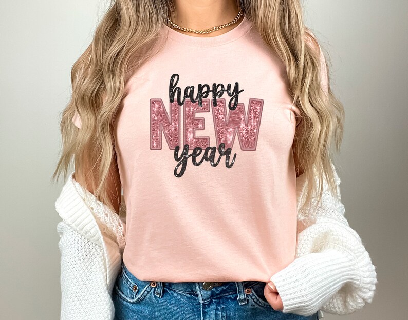 May include: A pink t-shirt with the text "happy new year" in black and pink glitter lettering.