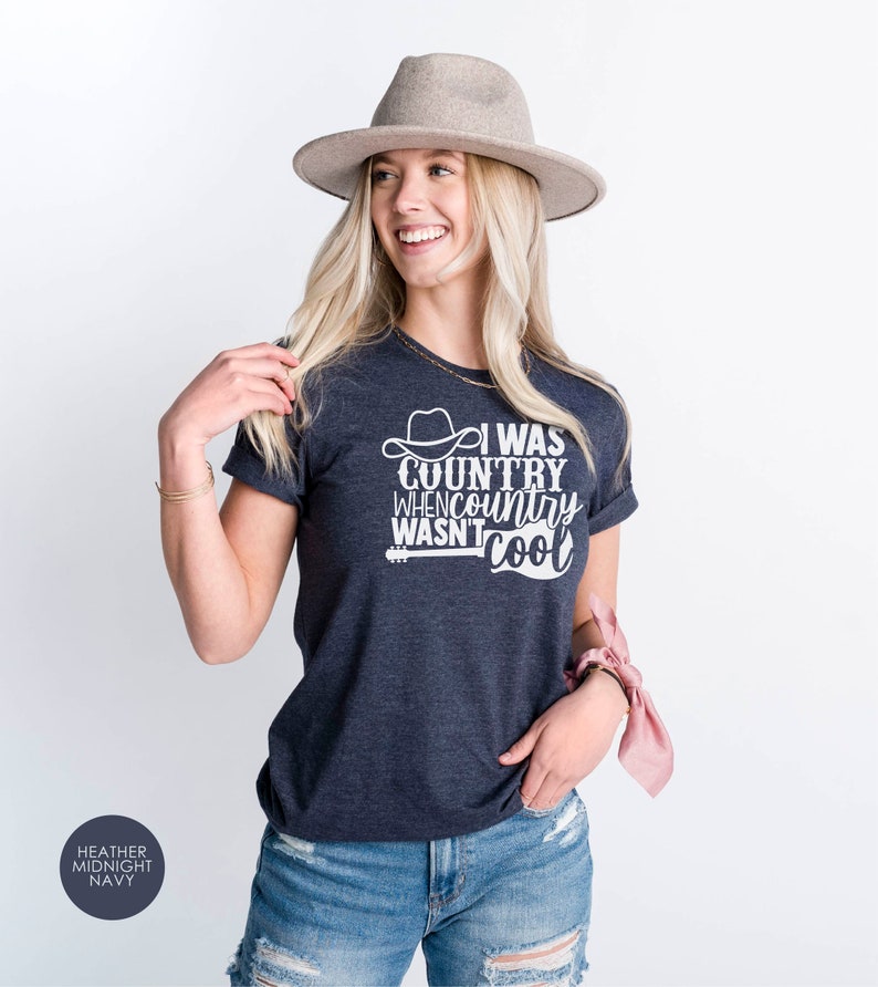 May include: A heather midnight navy t-shirt with a white graphic that says "I was country when country wasn't cool" with a cowboy hat and guitar graphic.