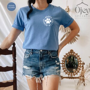 May include: A light blue t-shirt with a white paw print and the text "Adopt. Foster. Rescue." printed on the front.