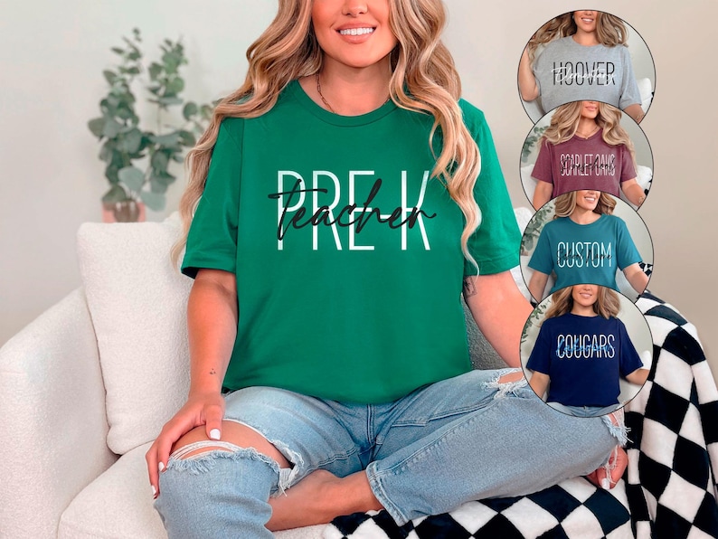 以下が含まれることがあります： 白と黒の文字で「PRE-K Teacher」と書かれた緑色のTシャツ。グレー、バーガンディ、ティール、ネイビーブルーのTシャツが追加で表示され、それぞれ異なるテキストが書かれています。その人はブルージーンズを履いています。