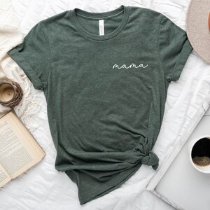 以下が含まれることがあります： ヘザーフォレストグリーンのTシャツ。前面に白い筆記体で「mama」と書かれている。