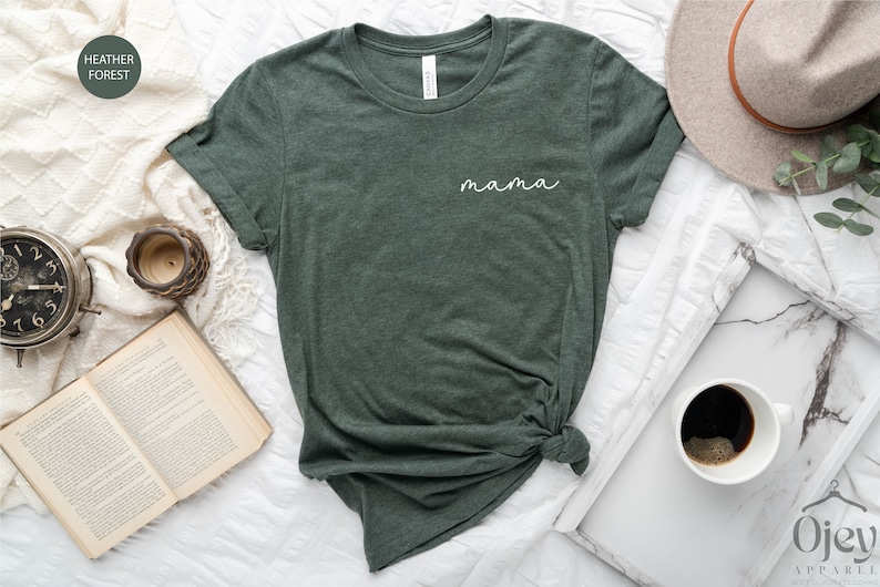 以下が含まれることがあります： ヘザーフォレストグリーンのTシャツ。前面に白い筆記体で「mama」と書かれている。