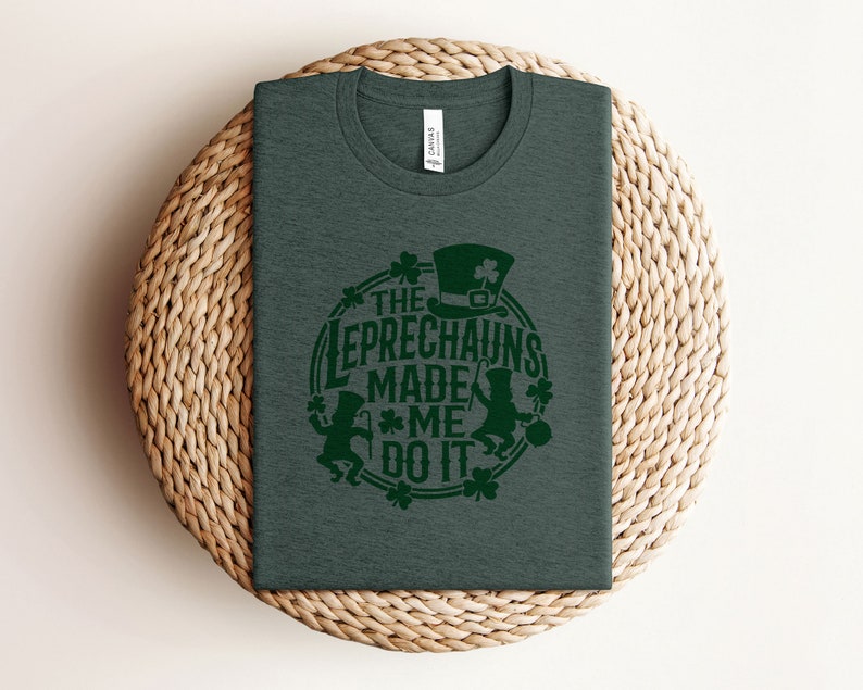 May include: A dark green t-shirt with a green shamrock design and the text "The Leprechauns Made Me Do It".
