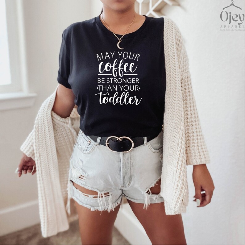May include: A black t-shirt with the text "May your coffee be stronger than your toddler" in white lettering.
