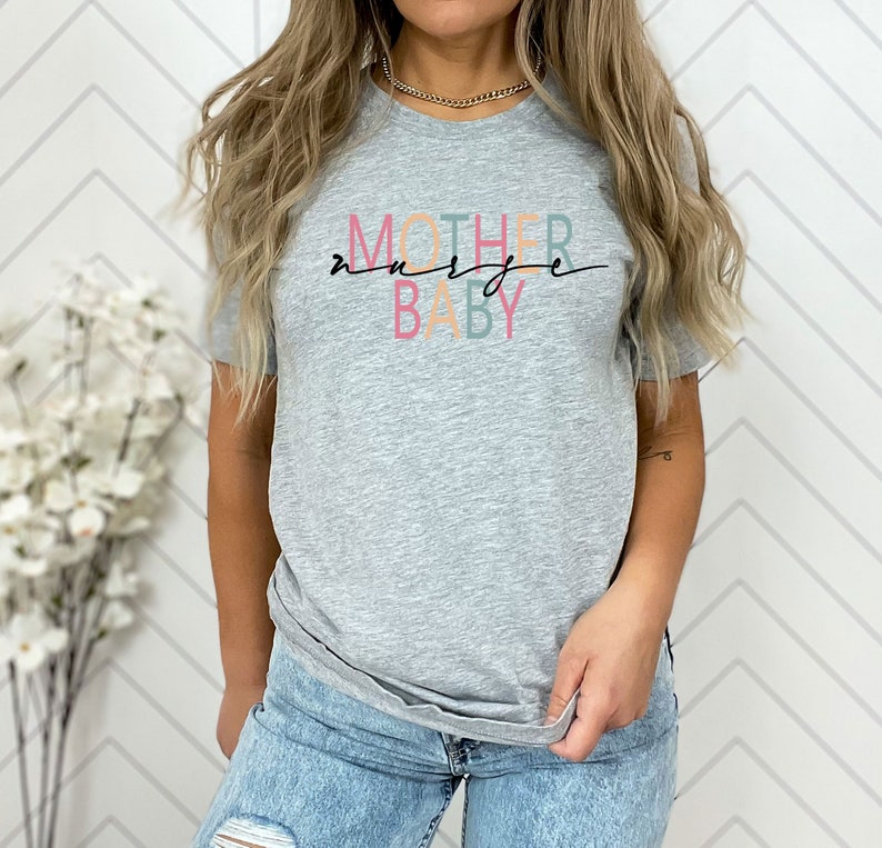 Puede incluir: Camiseta gris con el texto "MOTHER" en naranja, "NURSE" en verde y "BABY" en rosa.