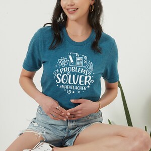 May include: A teal blue t-shirt with a white graphic design that says "Problems Solver" with math symbols and the hashtag "#mathteacher".