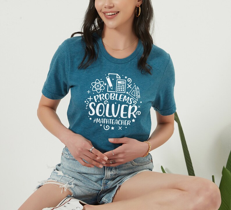 May include: A teal blue t-shirt with a white graphic design that says "Problems Solver" with math symbols and the hashtag "#mathteacher".
