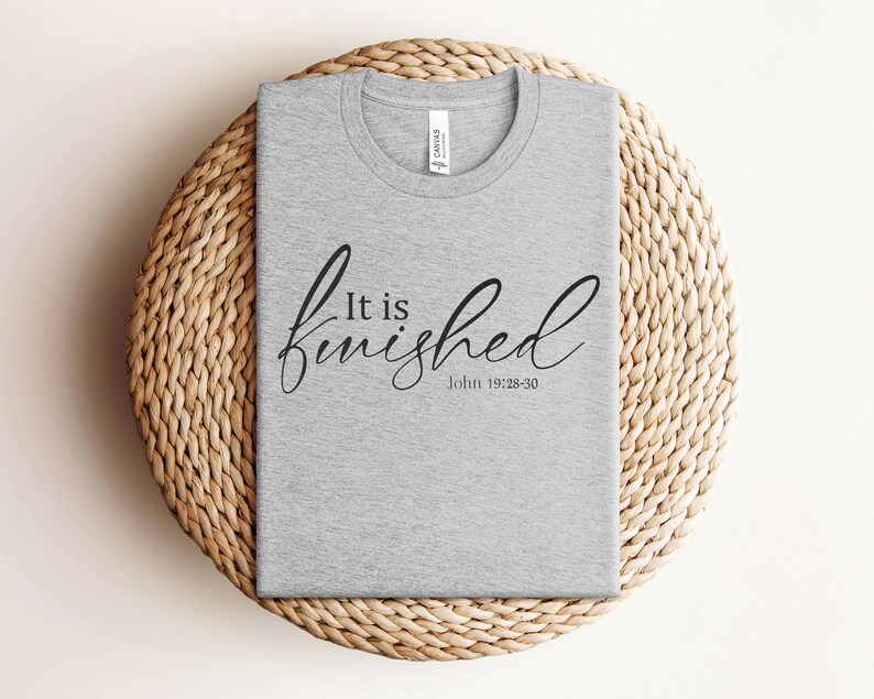 May include: A gray t-shirt with the text "It is finished" in black cursive lettering and the scripture reference "John 19:28-30" underneath.
