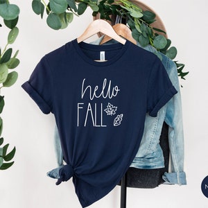 May include: Navy blue t-shirt with the text "hello fall" in white lettering and a simple leaf design.