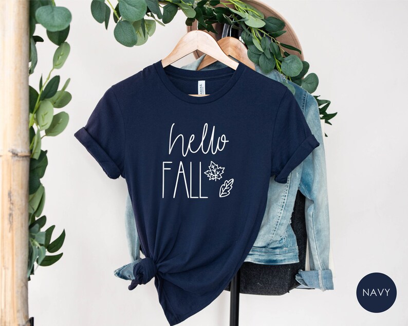May include: Navy blue t-shirt with the text "hello fall" in white lettering and a simple leaf design.