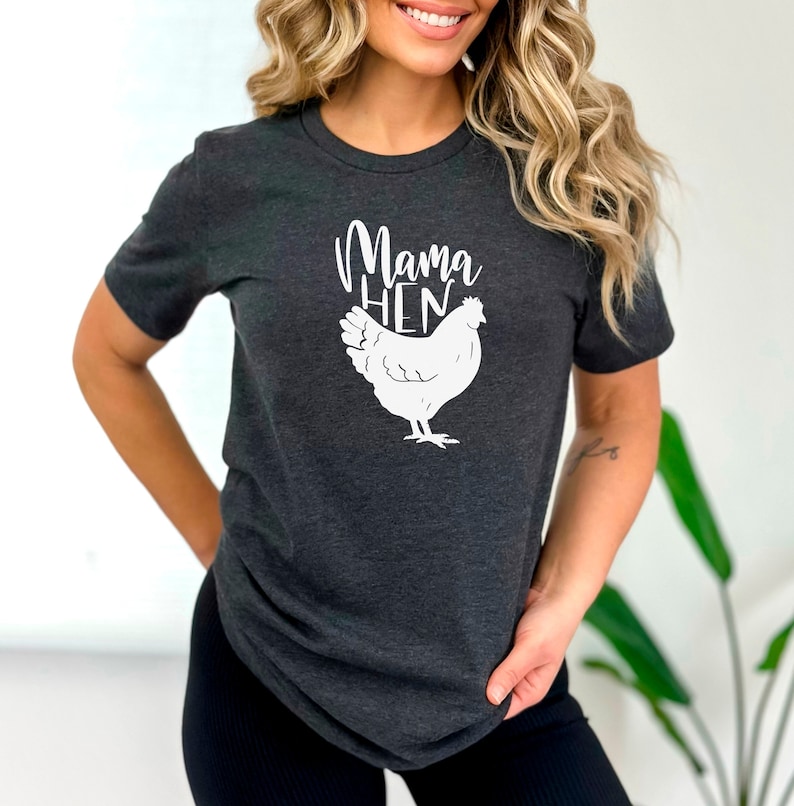 May include: A dark gray t-shirt with a white graphic of a chicken and the text "Mama Hen".