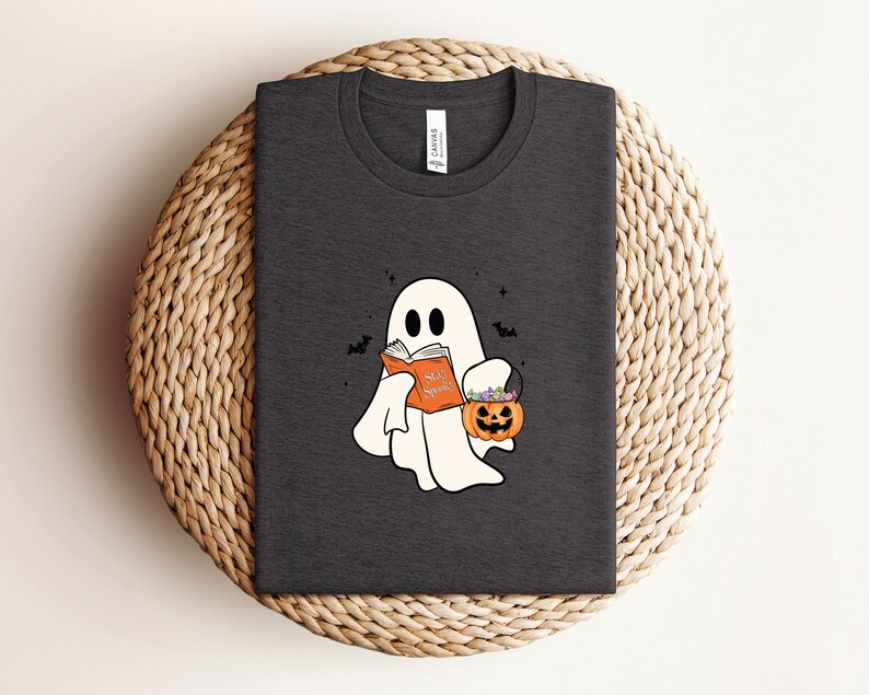 May include: A dark gray t-shirt with a white ghost holding a book that says "Scary Stories" and a pumpkin bucket with candy.