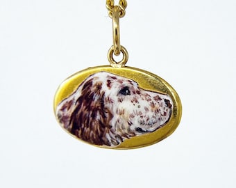 May include: A gold pendant necklace with a white and brown dog portrait enamel.