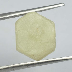 May include: A pale yellow, hexagonal, faceted gemstone with a rough, natural finish.