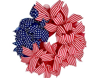 May include: A red, white, and blue patriotic wreath made of ribbon and mesh. The wreath is decorated with stars and stripes.