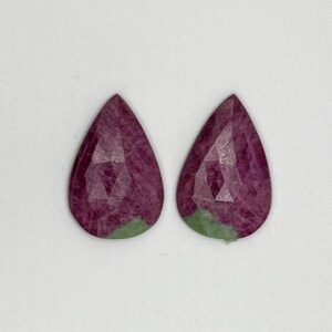 May include: A pair of pear-shaped gemstones with a pink and green colour pattern.