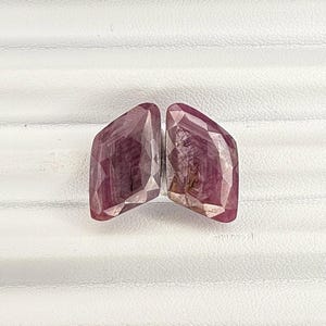 May include: Two pink gemstone cabochons with a faceted cut. The gemstones are set in a raw, natural style.