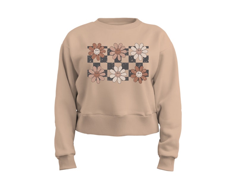 May include: A beige cropped sweatshirt with a checkered pattern and six smiling flower designs in shades of brown, pink, and white.