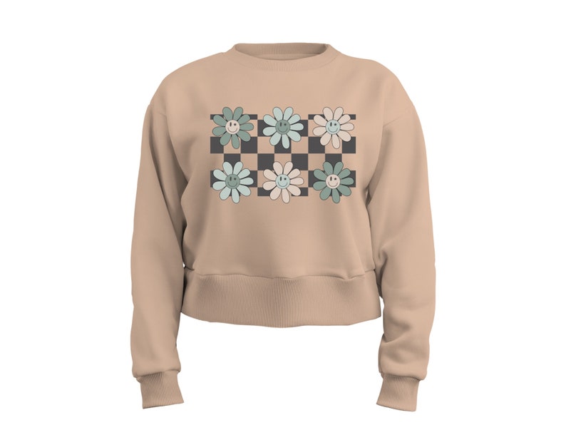 May include: A beige cropped sweatshirt with a checkered pattern in black and white. Six pastel green, blue, and pink flowers with smiley faces are arranged on the checkered pattern.