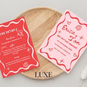 May include: Two wedding invitations in pink and red. The invitation on the left has the wedding details, including the location, gifts, and RSVP information. The invitation on the right has the names Erica and Tom, the wedding date, and the location. Both invitations feature a disco ball and hearts.