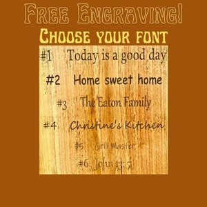 May include: A wooden board with six different font styles for engraving. The text on the board reads: "FREE ENGRAVING! CHOOSE YOUR FONT #1 Today is a good day #2 Home sweet home #3 The Eaton Family #4 Christine's Kitchen #5 Grill Master #6 John 13:7"