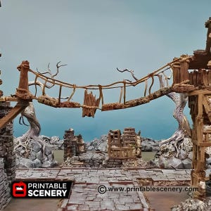 Puede incluir: Diorama detallado de un paisaje de fantasía con un puente de madera, estructuras de piedra y un suelo texturizado. El puente está hecho de madera envejecida y cuerda, con una sección rota. La escena incluye el texto "PRINTABLE SCENERY" y una dirección web.