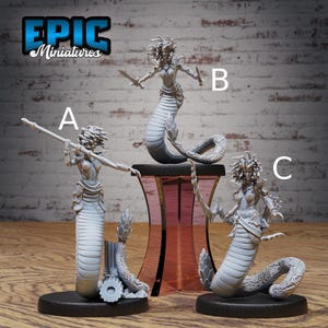 May include: Three gray Medusa miniatures with snake-like lower bodies and intricate details. One holds a spear, another a sword, and the third a staff. The Epic Miniatures logo is in the upper left corner.
