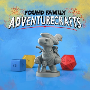 May include: A grey turtle figurine with a hat, backpack, and cane stands before blue, yellow, and red dice. The text "FOUND FAMILY ADVENTURECRAFTS" is above the figurine on a blue background.