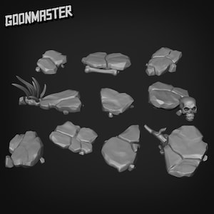May include: A selection of grey, stylised rocks and terrain elements, including a skull, bone, and vegetation. The text "GOONMASTER" is in the upper left corner. These elements are likely for tabletop gaming or miniature scenery.